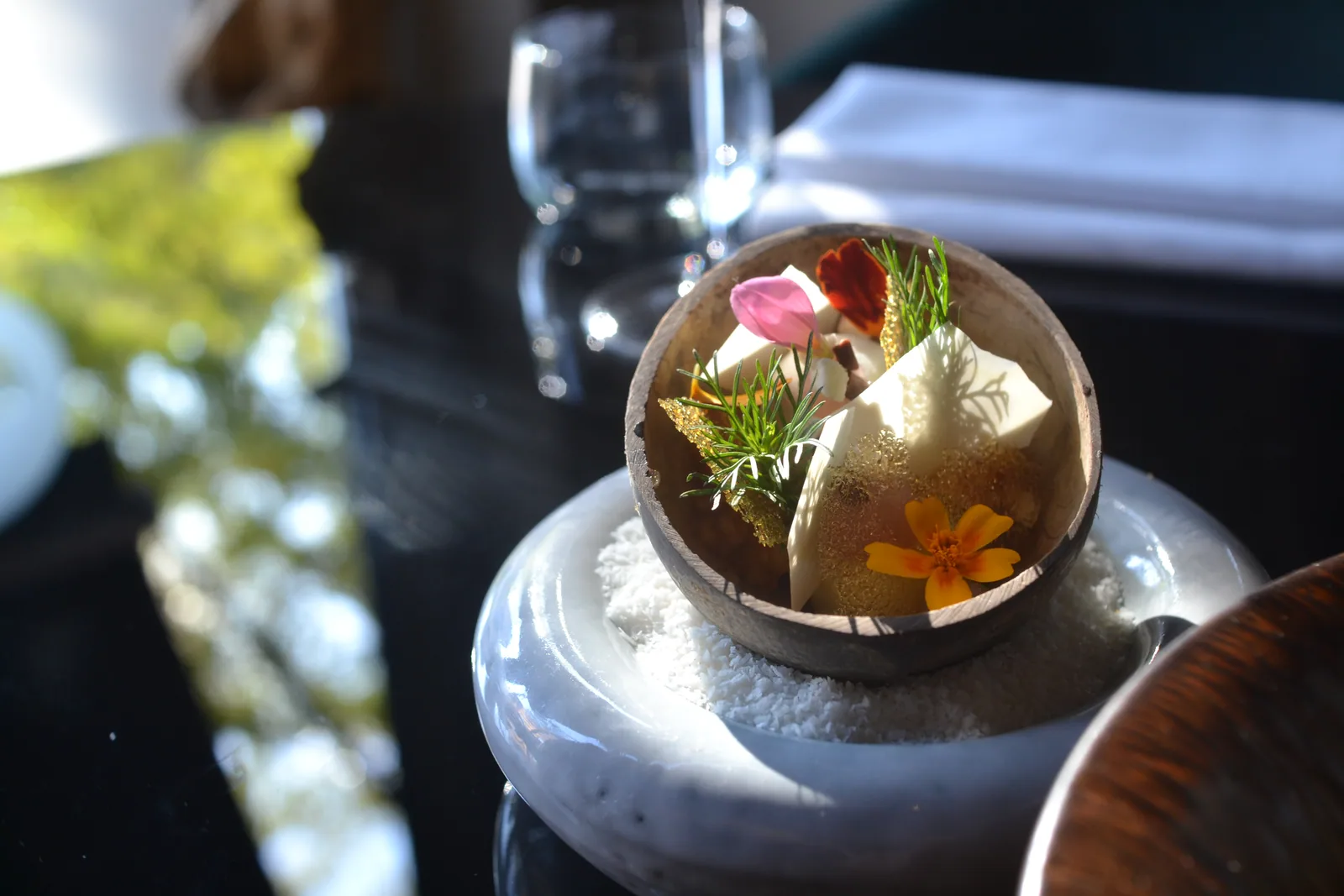 Dessert in een ronde schaal met bloemen, groene accenten en lichte garnituren.